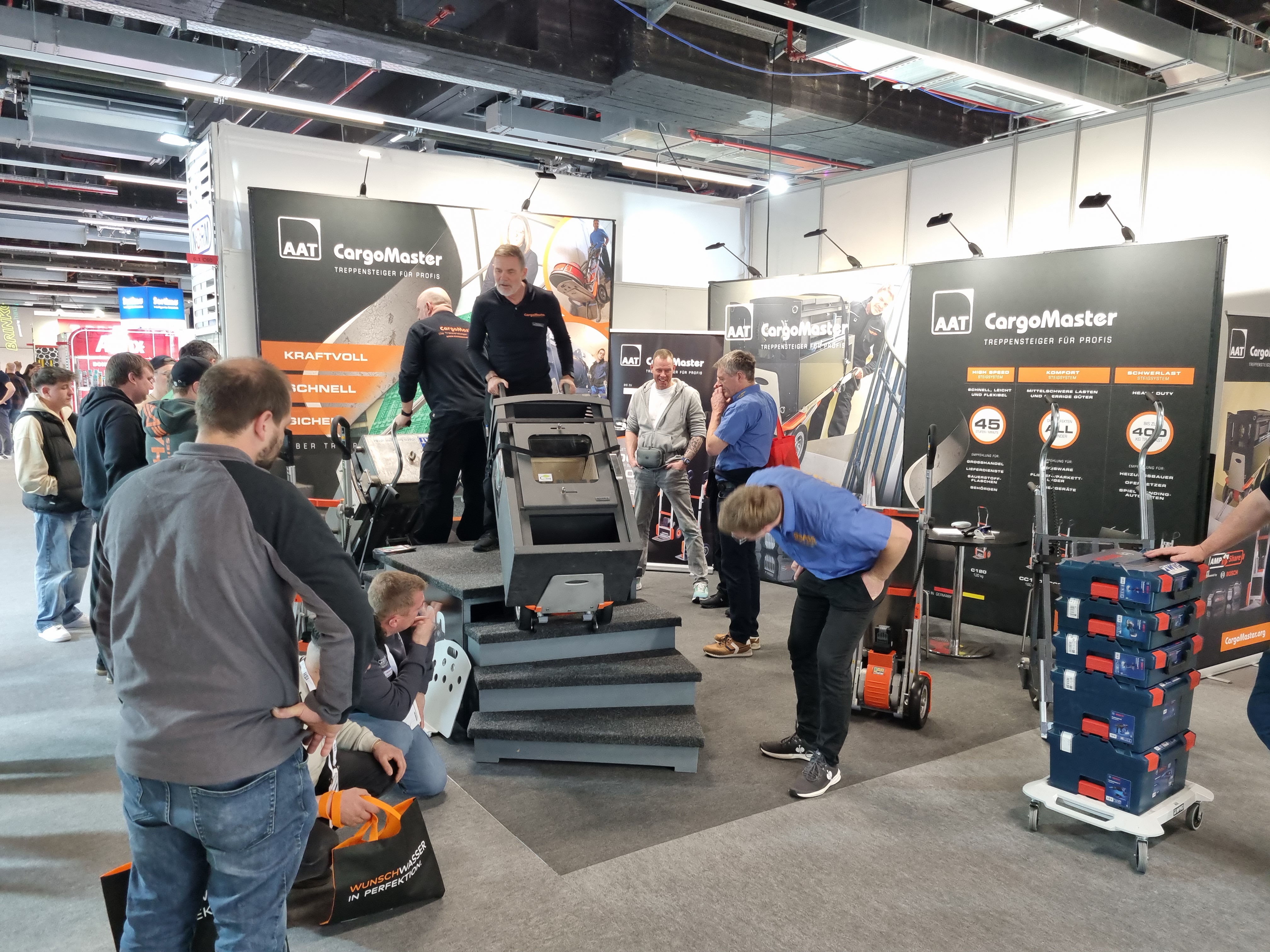 Das Bild zeigt einen unserer Mitarbeiter an unserem Messestand, der interessierten Besuchern unsere Geräte Cargomaster vorstellt.