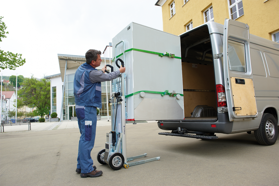 The image shows a man using a CargoMaster stair climber for loads to independently load a large machine into a van without any additional help.