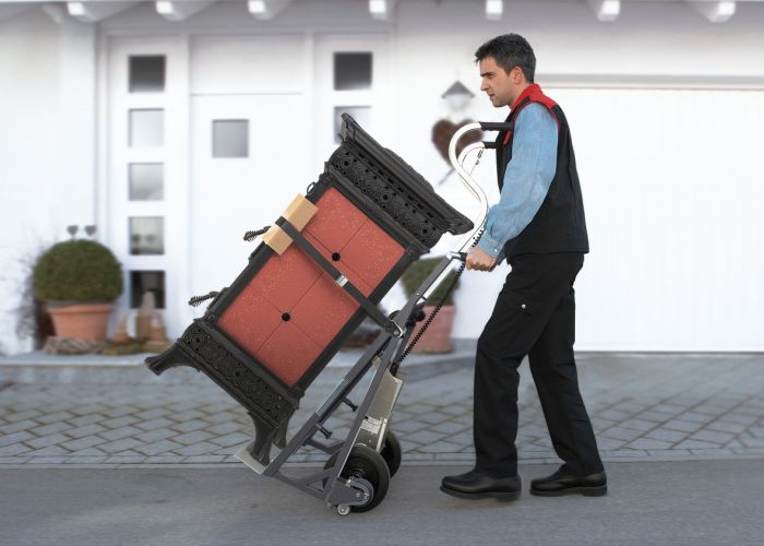 The picture shows a man using a CargoMaster stair climber for loads to push an oven across the floor with ease.